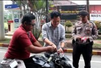 Kasat Intelkam Polres Langkat AKP Muliono memasang bendera merah putih di kendaraan warga.