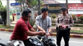 Kasat Intelkam Polres Langkat AKP Muliono memasang bendera merah putih di kendaraan warga.