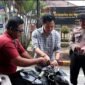 Kasat Intelkam Polres Langkat AKP Muliono memasang bendera merah putih di kendaraan warga.